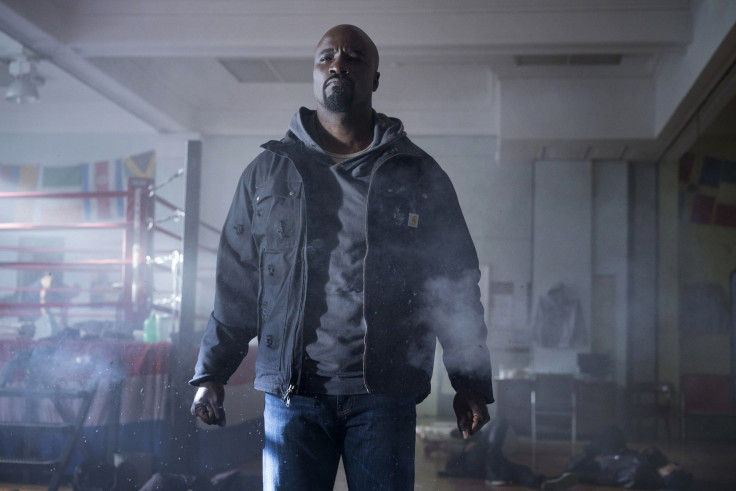 Luke Cage wears a Carhartt utility jacket with an plain light blue fixed-hood pullover hoodie. 