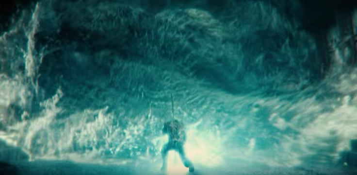 Aquaman stops a tidal wave with his trident. 