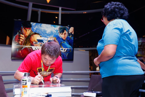  'Street Fighter' series Executive Producer, Yoshinori Ono (L) signs autographs during the Annual Gaming Industry Conference E3 at the Los Angeles Convention Center on June 16, 2015 in Los Angeles, California. 