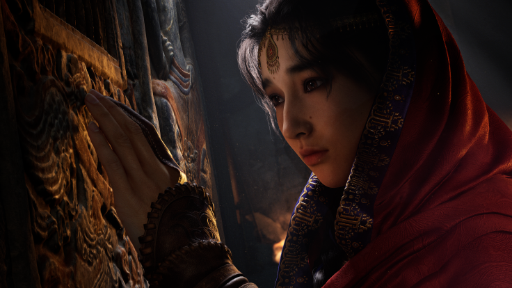 Woman in red robe touching carved stone wall